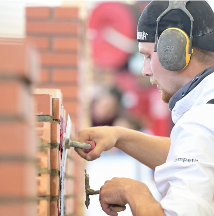 Ein Maurer mit Kopfhörern bei den WorldSkills 2024 der WM der Berufe